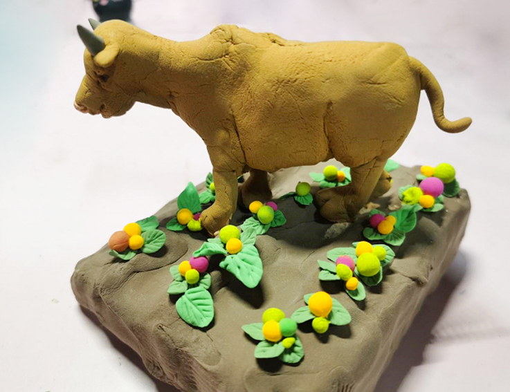 泥和塑料泡沫材料创作作品《希望的田野》,形象地表达出老黄牛在田间